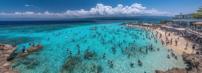 Tłum ludzi kąpiący się w turkusowej wodzie tropikalnej zatoki przy piaszczystej plaży w słoneczny dzień. © Avrilin