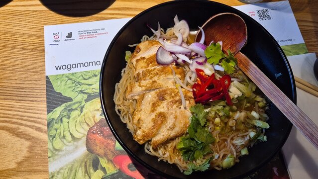 London UK 02.07.2025 asian noodle soup with grilled chicken and fresh vegetables served in wagamama restaurant creating vibrant street food dining experience