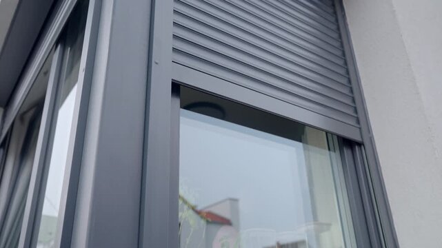 Close-up of modern exterior window with metal roller shutter moving down. Concept of home security privacy weather protection and residential architecture.