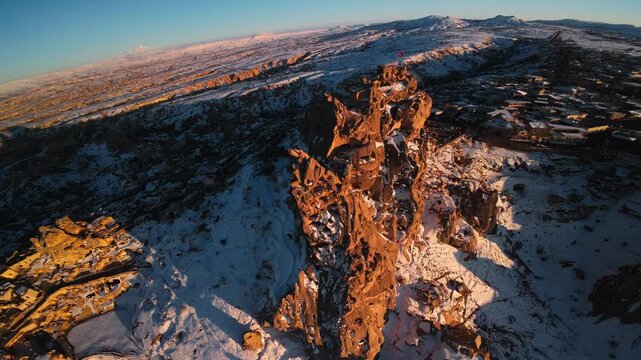 Dynamic FPV drone flight over Uchisar Castle summit passing near Turkish flag at sunset in winter, Cappadocia, Turkey