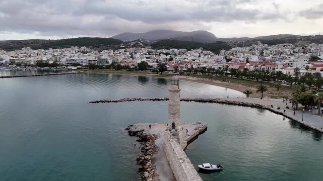 Scenic aerial footage moving past the old venetian lighthouse and the city of rethymno in greece
