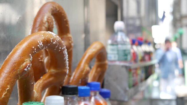 Pretzel for sale, street food in Manhattan, New York City, United States. Fast food counter, stall or kiosk, traditional pastry snack and soda drinks to go in NYC. Baked bread dessert, food on the go.