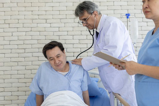 Doctor exam senior patient in hospital bed while nurse taking notes, healthcare team providing medical care, diagnosis, treatment and patient support concept in clinical.