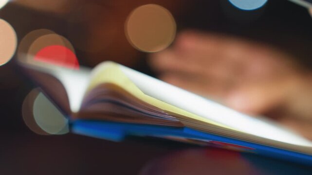 Shallow focus pages turning with bokeh, detailed edge and binding of illustrated book, glossy color shapes and soft blur, slow flip motion creating dreamy night mood and quiet wonder.