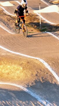 Vertical Action Shot of Young Rider on BMX Racing Track with Helmet and Safety Gear