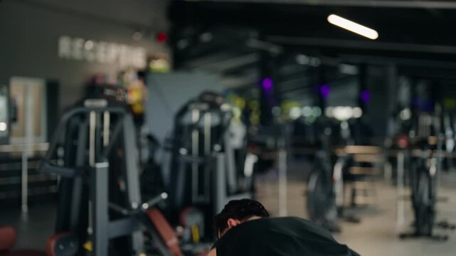 Caucasian athlete intensely training his upper body performing the landmine press exercise, a functional full body workout, inside a modern fitness club with professional equipment