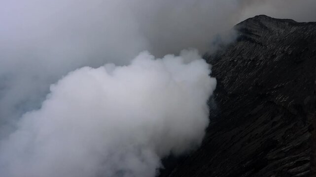 The interior of Mount Bromo volcano, where thick white volcanic steam billows upward from active vents within the crater in East Java, Indonesia