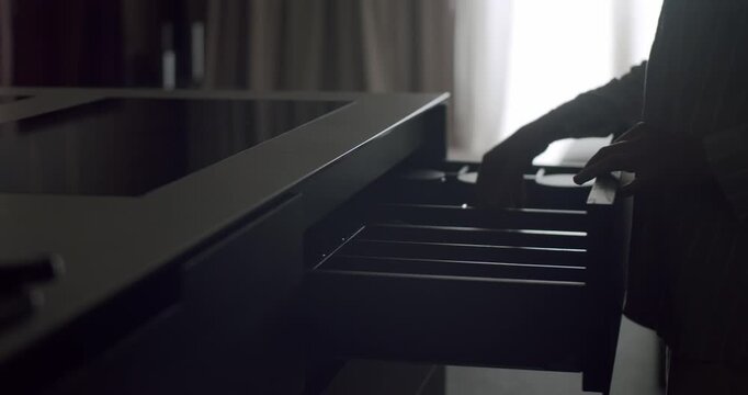 Moody and mysterious silhouette of a person holding a knife over open drawers in a dimly lit kitchen. Silhouette of a Person Holding Knife Over Drawers in a Dimly Lit Kitchen