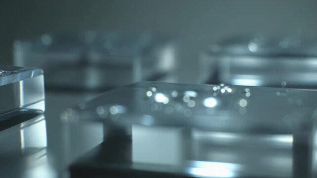 Water drops splashing and bouncing on clear glass slides, forming intricate liquid structures and ripples under blue highlights, evoking laboratory research and microscopic analysis