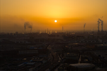 Naklejka premium Sunset over industrial cityscape in Jiayuguan City, China with smoke stacks emitting plumes