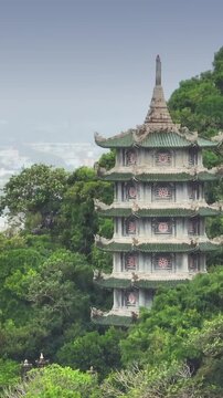 A scenic view of the Marble Mountains featuring the Xa Loi Tower, a pagoda, surrounded by lush greenery in Da Nang, Vietnam. It's a popular tourist destination.