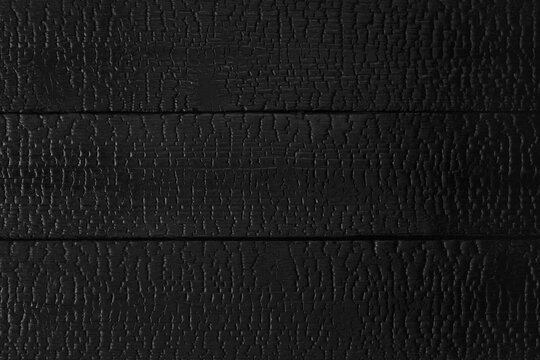 Charred wood texture background with burned surface and deep grain