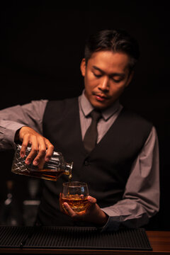 Bartender Holding Out a Glass of Premium Whiskey to Customer