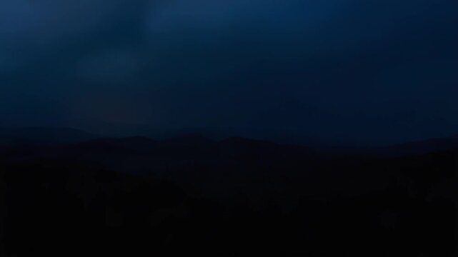 Lightning electrifying the dark night sky over misty mountain ridges and a valley floor, creating a dramatic natural scene during a powerful electrical storm