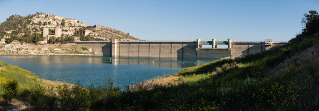 Panoramic massive concrete dam infrastructure at Amadorio Reservoir in Spain.