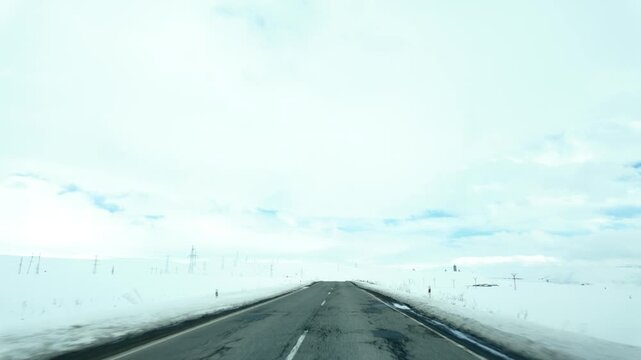 Car driving along a snowy road in winter conditions. Cold weather, snow-covered landscape and transportation concept.