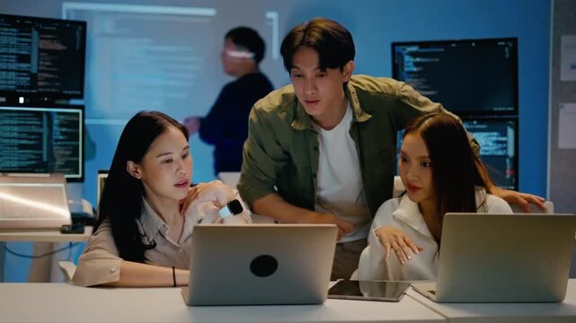 Asian business team of programmer working and Ai coding in night office.Professional software engineer training and collaborate on project script with laptop.Concept of Ai agent,digital tech startup