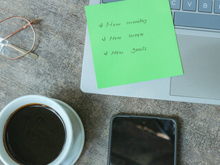 Naklejka premium Green Sticky Note on Laptop with Coffee Cup and Smartphone in Workspace