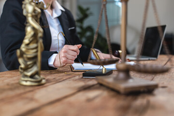Fototapeta premium Legal professional writing documents with scales of justice