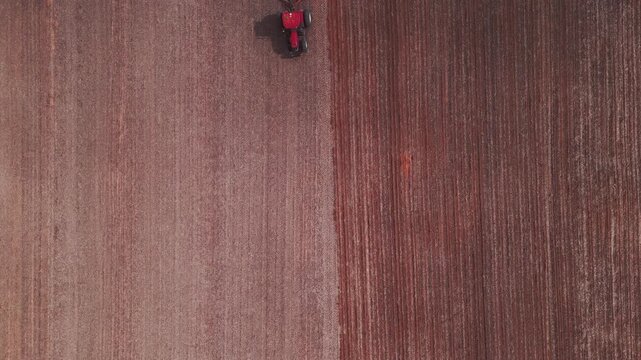 Tractor pulling precision planter seeding crop rows in Formosa, Goi&aacute;s, Central-West Brazil, mechanized agriculture with controlled spacing and soil preparation, top down aerial view, static shot.