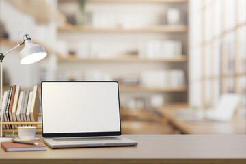 White screen laptop with coffee and book under lamp light on wooden table counter in cafe or library © bongkarn