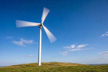 Fototapeta premium Large white wind turbine generating clean renewable energy against a blue sky