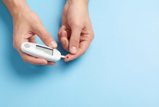 Male hands using a modern glucometer to test blood sugar level