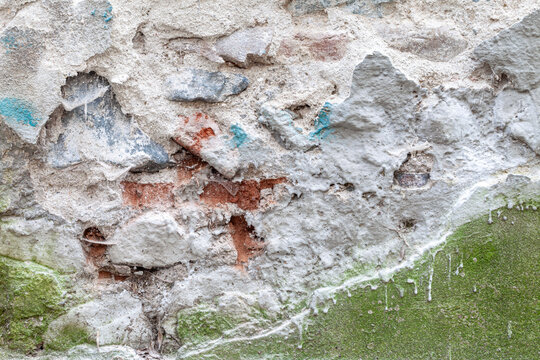 Diferent plaster materials covering an old brick and stone wall background texture