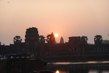 Fototapeta premium Wide panoramic view of Angkor Wat temple silhouette at sunrise, iconic Khmer architecture reflected in the water under a soft morning sky, Cambodia.