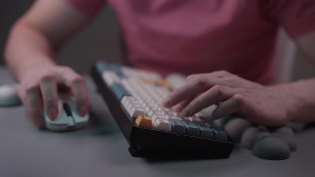 Person typing on mechanical keyboard using ergonomic wrist rest for carpal tunnel syndrome prevention while playing video game or working on computer, close-up, slow motion.