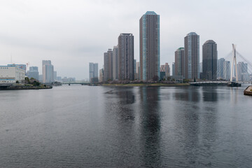 Obraz premium 東京ウォーターフロント Tokyo waterfront cityscape with high-rise buildings and canal on a cloudy spring day
