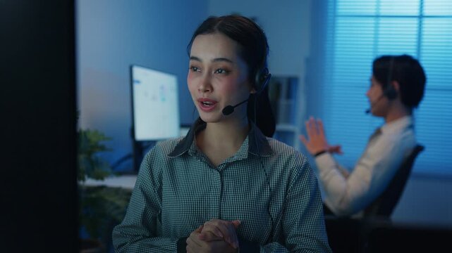 Gen z Asia young call center team or customer support service executive use computer and microphone headset work technical e commerce support in late night office. Telemarketing or sales job concept.