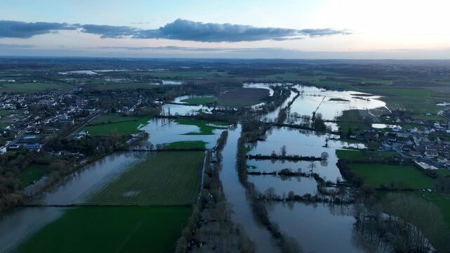 Aerial panorama of severe flooding in Sarthe department showing submerged fields roads and houses with distant town under cloudy sky