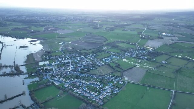 Wide aerial view of extensive flooding in Sarthe department with submerged fields village buildings and distant horizon under overcast sky