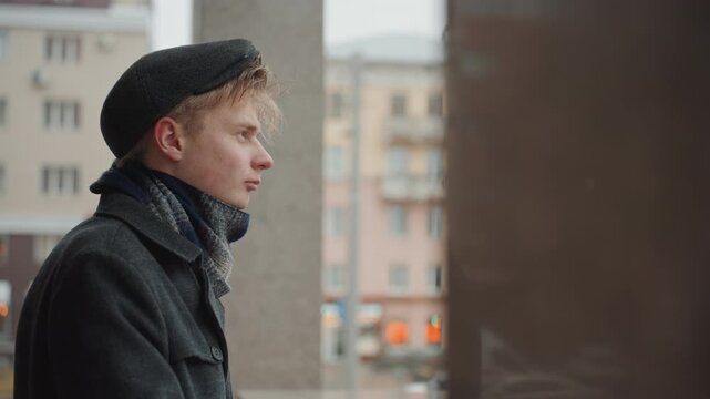 Profile of artist observing urban environment. Quiet cinematic portrait of maker amidst city surroundings. Elegant depiction of creator wearing beret and scarf observing street activity