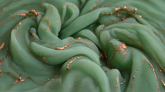 A close-up view of a sage green fabric with gold sequins spread out in a textured, wavy pattern on a white surface.
