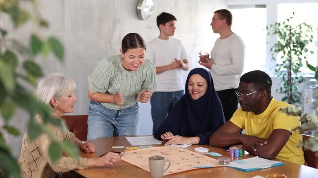 Group of multinational students of different years play a board game with passion