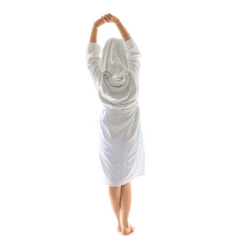 Woman in white bathrobe stretching in hotel room. Female guest enjoying morning relaxation after sleep. Concept of wellness, spa treatment and comfort in luxury hospitality accommodation.