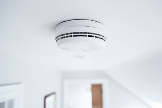 Shallow focus of a newly fitted mains operated smoke alarm detector seen in the upstairs landing of a modern house. One of two detectors, the other downstairs in the hallway.
