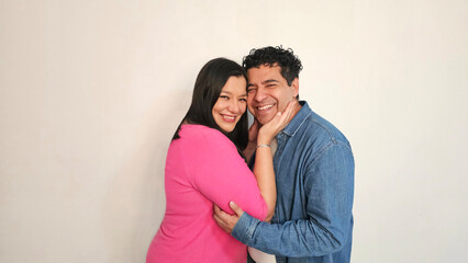 Fototapeta premium Latino man and woman in their 40s show their love to celebrate Valentine's Day and their anniversary with kisses and hugs, laughing and smiling