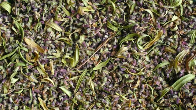 Aromatic pile of dried thyme, a popular culinary herb and seasoning, rotating in a seamless loop. This top down view shows the intricate texture of the purple flowers and green leaves