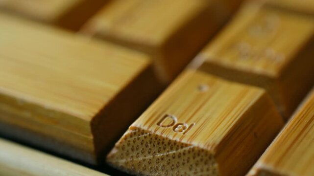 Close up shot of a finger pressing a key delete on an elegant eco friendly wooden keyboard, highlighting the concepts of sustainability, modern technology, and environmental responsibility