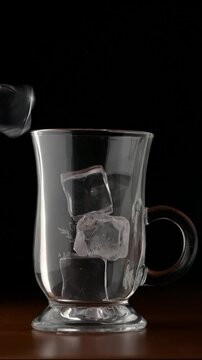 Ice Cubes Falling into Glass, Macro Close Up Extreme close up of crystal ice cubes falling into a clear glass. Dynamic motion, sharp splash details, and transparent frozen texture captured in high def