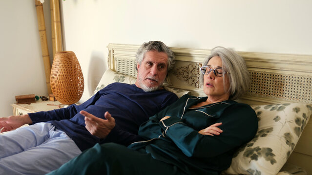 Upset senior couple in bed having an argument about their relationship