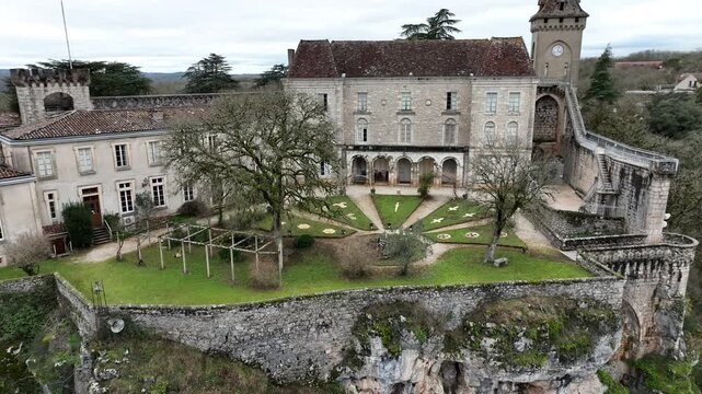 Aerial view of Rocamadour beautiful formal garden courtyard with patterned lawn and trees inside historic stone buildings complex