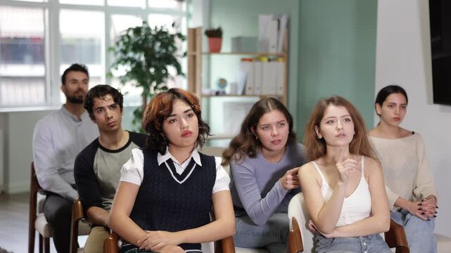 Woman gives a presentation to a small audience in a modern office and classroom. Young teacher showing materials to students in class
