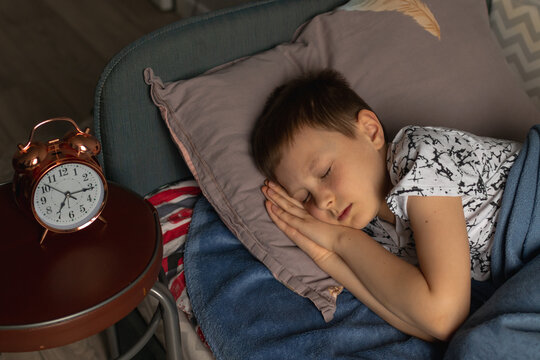 9 years old boy sleeping in bed, but  it's  time to wake up for school