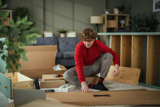 Young man assembling new furniture in living room