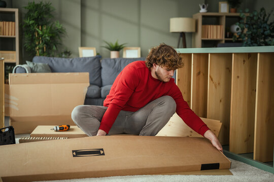 Young man assembling new furniture in living room