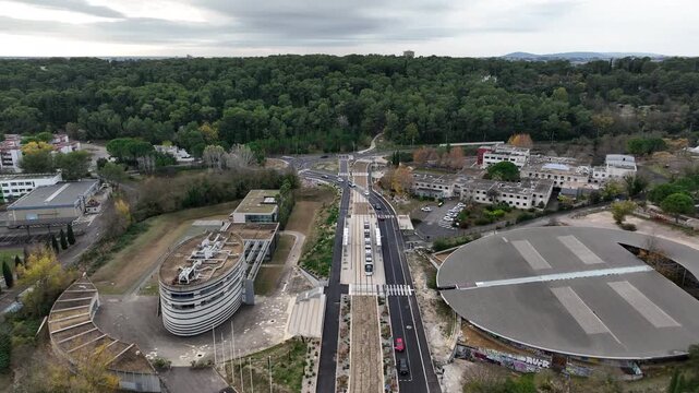 Aerial view of Montpellier tramway modern circular station and tram tracks surrounded by dense green forest and urban infrastructure